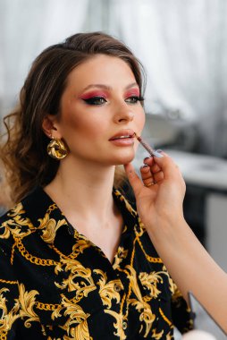 Güzel, modern bir güzellik salonunda, profesyonel bir makyöz genç bir kız için makyaj yapar. Güzellik ve moda.