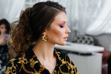 Güzel, modern bir güzellik salonunda, profesyonel bir makyöz genç bir kız için makyaj yapar. Güzellik ve moda.