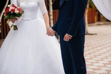 Güzel ve sofistike bir düğün buketi gelini damadın yanında tutuyor. Düğün buketi ve yüzükler.