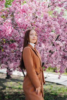 Güzel bir genç kız, bahar günü çiçek açan bir elma bahçesinde yürür. Yaşam tarzı, eğlence.