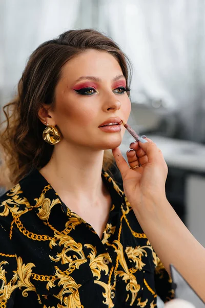 Güzel, modern bir güzellik salonunda, profesyonel bir makyöz genç bir kız için makyaj yapar. Güzellik ve moda.