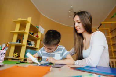 Genç bir anne evde oğluyla ev ödevi yapıyor. Ebeveynler ve eğitim