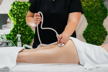 Genç ve güzel bir kız Spa 'da profesyonel bir elektrik süpürgesi masajının keyfini çıkarıyor. Vücut bakımı. Güzellik salonu