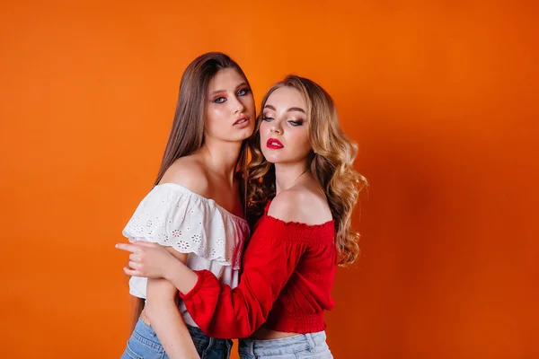 Két Fiatal Gyönyörű Lány Érzelmeket Mosolyt Mutat Stúdióban Narancssárga Alapon — Stock Fotó