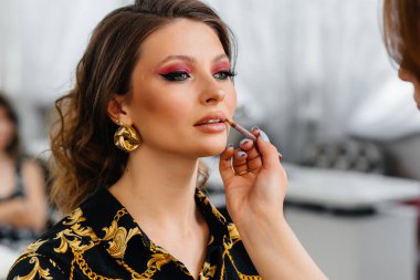 Güzel, modern bir güzellik salonunda, profesyonel bir makyöz genç bir kız için makyaj yapar. Güzellik ve moda.