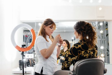 Güzel, modern bir güzellik salonunda, profesyonel bir makyöz genç bir kız için makyaj yapar. Güzellik ve moda.