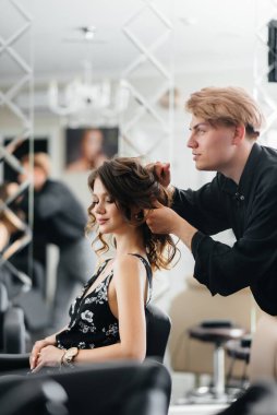 Güzel, modern bir güzellik salonunda, profesyonel bir stilist genç bir kız için saç ve saç kesimi yapar. Güzellik ve moda.
