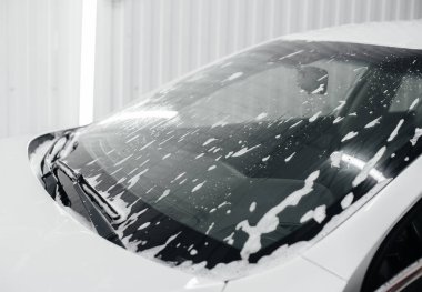 Köpüklü modern yıkama ve beyaz bir arabanın yüksek basınçlı suyu. Araba yıkama