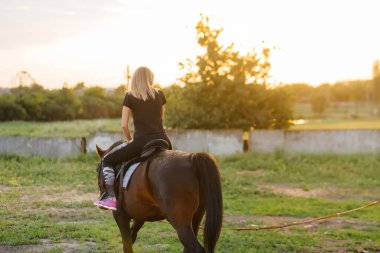 Genç ve güzel bir kız, bir yaz günü çiftlikte safkan bir Mare 'ye binmeyi öğreniyor. At binme, eğitim ve rehabilitasyon