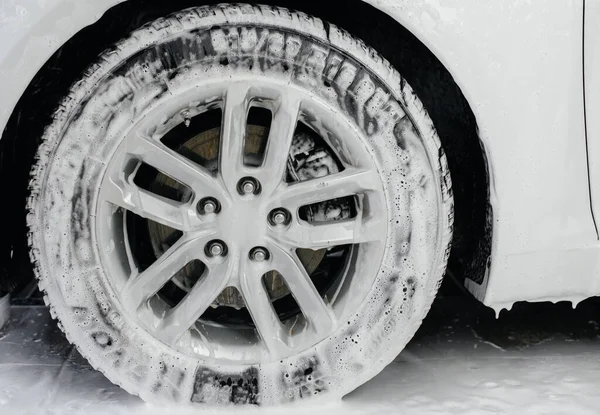 Modern washing of car wheels with foam and high water pressure. Car wash