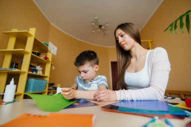 Genç bir anne evde oğluyla ev ödevi yapıyor. Ebeveynler ve eğitim