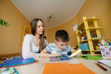 Genç bir anne evde oğluyla ev ödevi yapıyor. Ebeveynler ve eğitim