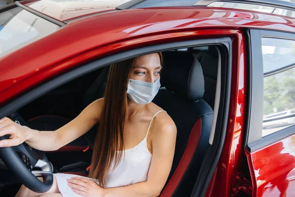 在流行病流行期间 一位年轻漂亮的姑娘戴着面具在一家汽车经销店检查一辆新车 在潘德米亚时期 汽车的销售和购买 — 图库照片