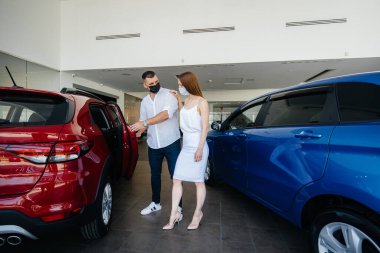 Maskeli genç bir çift yeni bir araç seçiyor ve salgın sırasında bayiliğin temsilcisine danışıyor. Araba satışları ve salgın sırasında hayat.