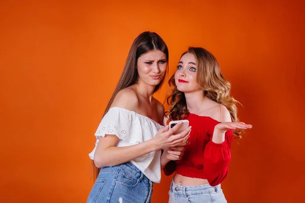 若く美しい2人の女の子が自撮りをして 紫色の背景でスタジオで電話を見ています 広告のための女の子 — ストック写真