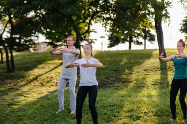 Bir grup insan gün batımında parkta yoga yapıyor. Sağlıklı yaşam tarzı, meditasyon ve sağlık