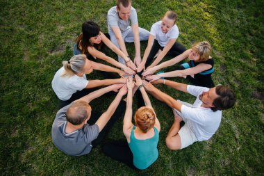 Bir grup insan gün batımında açık havada yoga yapıyor. Sağlıklı yaşam tarzı, meditasyon ve sağlık