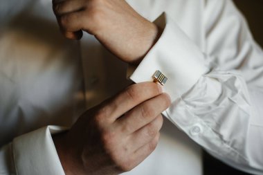 Şık genç adam kol düğmelerinin düğmelerini ilikliyor. Biçim