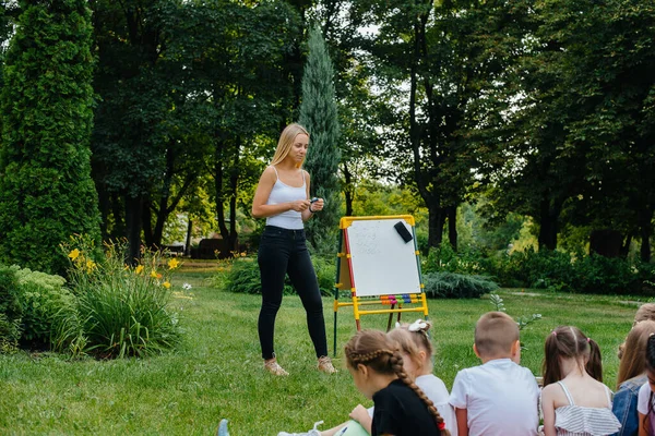 A teacher teaches a class of children in an outdoor Park. Back to school, learning during the pandemic