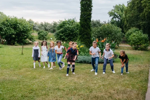 A group of school children runs in the Park in the summer. Happiness, lifestyle. Happy childhood