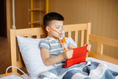 Bir çocuk akciğer solunumu sırasında tabletle oynuyor. İlaç ve bakım
