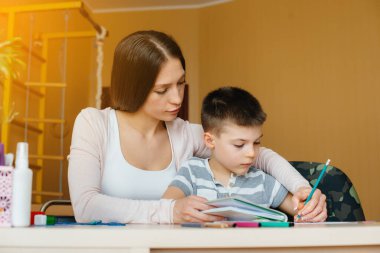 Genç bir anne evde oğluyla ev ödevi yapıyor. Ebeveynler ve eğitim