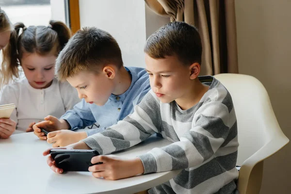 Los Niños Sientan Una Mesa Café Juegan Juntos Los Teléfonos — Foto de Stock