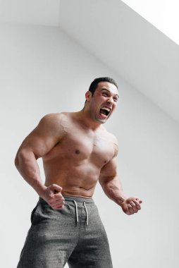 Sportif bir adam öfkeyle beyaz bir arka plana bağırıyor. Öfke. Tehdit