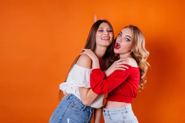 Duas Meninas Jovens Bonitas Mostram Emoções Sorrisos Estúdio Fundo Laranja — Fotografia de Stock