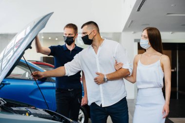 Maskeli genç bir çift yeni bir araç seçiyor ve salgın sırasında bayiliğin temsilcisine danışıyor. Araba satışları ve salgın sırasında hayat.