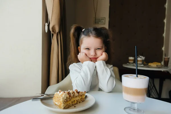 Uma Menina Bonita Está Sentada Café Olhando Para Bolo Cacau — Fotografia de Stock