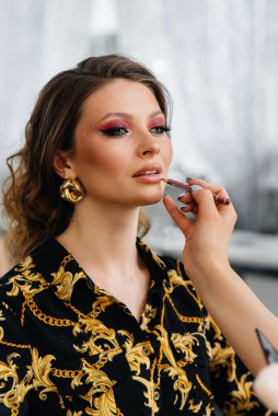 Güzel, modern bir güzellik salonunda, profesyonel bir makyöz genç bir kız için makyaj yapar. Güzellik ve moda.