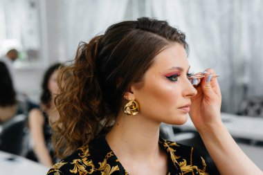 Güzel, modern bir güzellik salonunda, profesyonel bir makyöz genç bir kız için makyaj yapar. Güzellik ve moda.