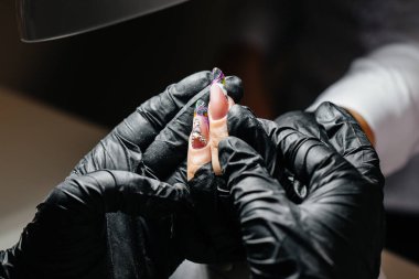 Genç bir kız bir güzellik salonunda ellerine manikür yaptırıyor. Güzellik salonu