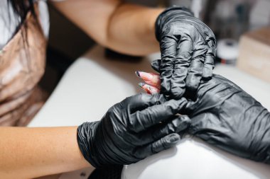 Genç bir kız bir güzellik salonunda ellerine manikür yaptırıyor. Güzellik salonu