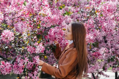 Güzel bir genç kız, bahar günü çiçek açan bir elma bahçesinde yürür. Yaşam tarzı, eğlence.
