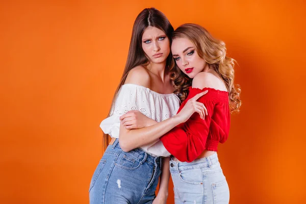 Dvě Mladé Krásné Dívky Ukazují Emoce Úsměvy Ateliéru Oranžovém Pozadí — Stock fotografie