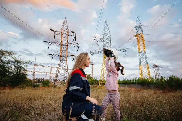 小さな女の子が母親のヘルメットを工学作業員につけている 将来の世代と環境への懸念 エネルギー — ストック写真