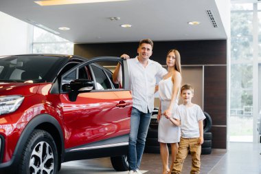 Mutlu genç bir aile araba galerisinden yeni bir araba seçer ve satın alır. Yeni bir araba alıyorum.