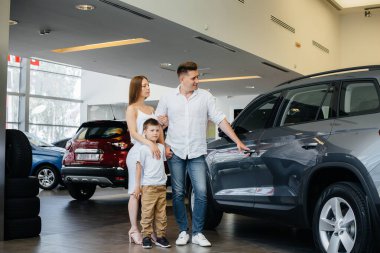 Mutlu genç bir aile araba galerisinden yeni bir araba seçer ve satın alır. Yeni bir araba alıyorum.