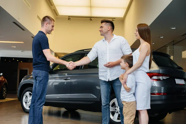 A happy young family chooses and buys a new car at a car dealership. Buying a new car