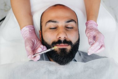 Dudak büyütme ve sakallı bir adam için kırışıklık giderme için estetik ameliyat. Kozmetoloji