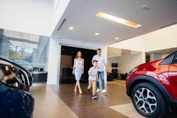 A happy young family chooses and buys a new car at a car dealership. Buying a new car