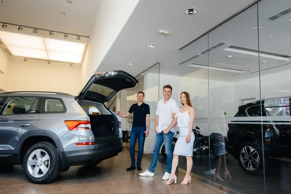 Uma Jovem Família Feliz Escolhe Compra Carro Novo Uma Concessionária — Fotografia de Stock