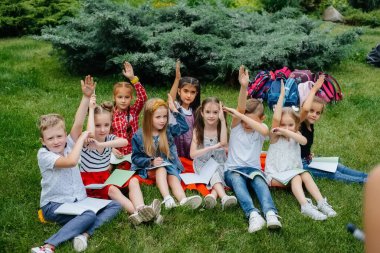 Bir öğretmen açık hava parkında bir sınıf çocuğa ders veriyor. Okula dönüyorum, salgın sırasında öğreniyorum.
