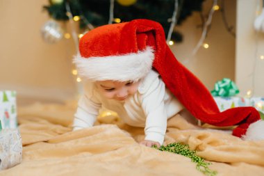 Sevimli gülümseyen bebek, Noel ağacının altında yatıyor ve hediyelerle oynuyor. Noel ve Yeni Yıl kutlamaları