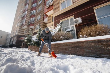 Güneşli ve soğuk bir günde genç bir adam evin önündeki karı temizler. Sokakları kardan temizliyorum..