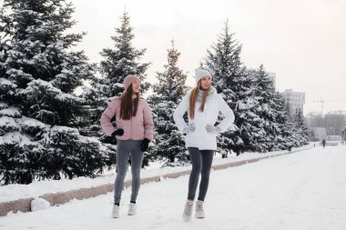 Güneşli bir kış gününde yürüyen ve spor yapan iki genç atletik kız. Sağlıklı bir yaşam tarzı.
