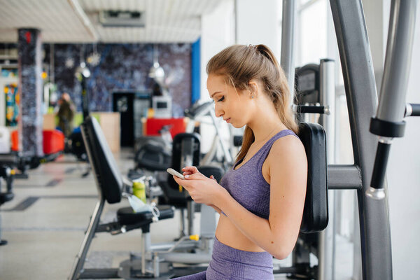 A young athlete uses her phone in the gym and takes a selfie.