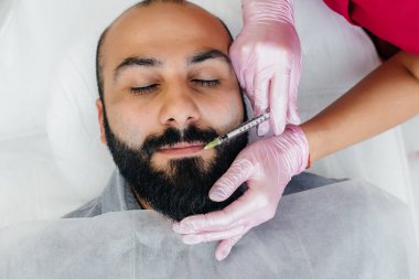 Dudak büyütme ve sakallı bir adam için kırışıklık giderme için estetik ameliyat. Kozmetoloji